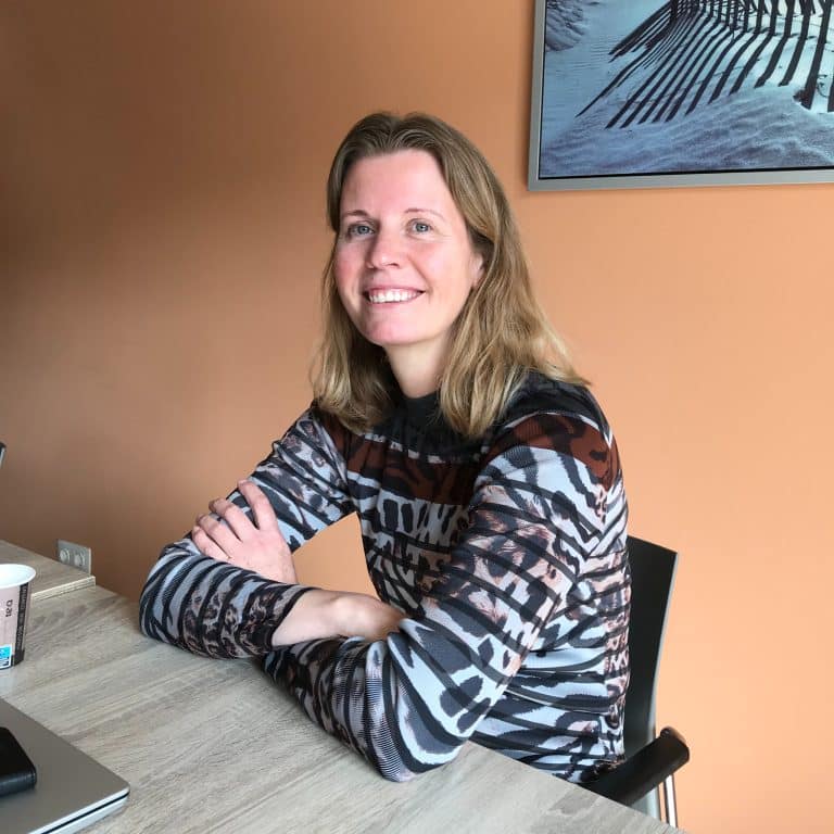Nathalie zit met een lach op haar gezicht achter haar bureau