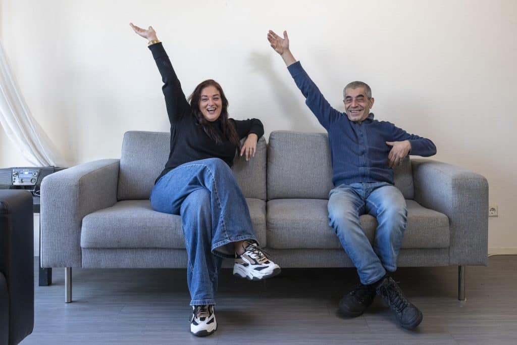 Man en vrouw zitten feestelijk met hand omhoog op de bank