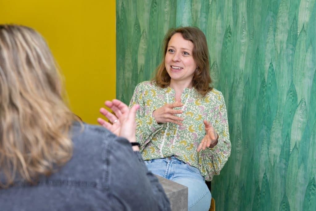 Vrouw naar camera en vrouw met rug naar camera in gesprek